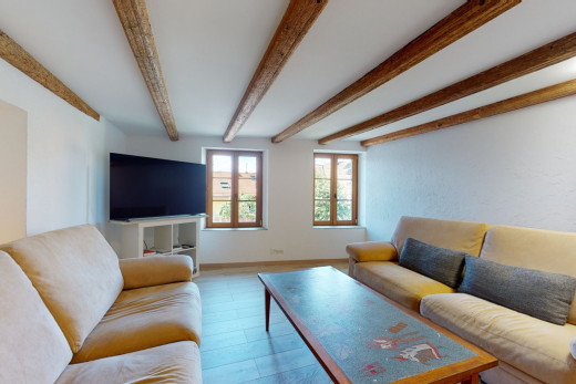 wohnzimmer mit balkendecke, natürliches licht und fernseher