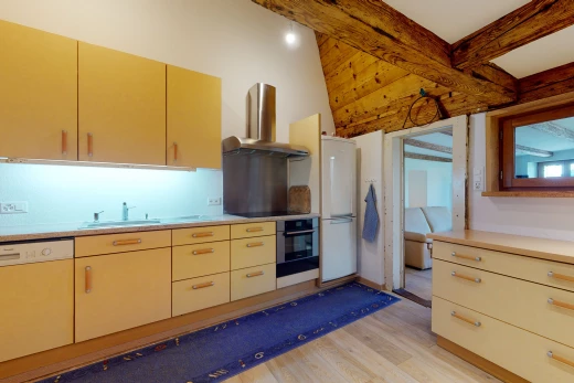 cuisine avec parquet, réfrigérateur, hotte, cuisinière électrique, four, lave-vaisselle, armoires marrons, et comptoirs claires