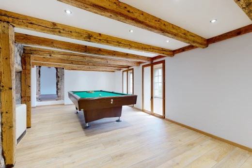 salle de jeux avec poutres apparentes, lumière naturelle, et parquet