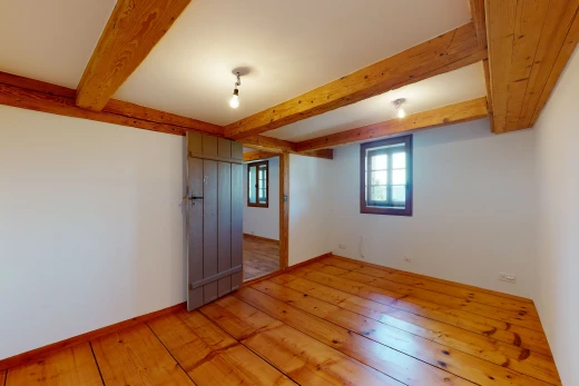 chambre vide avec parquet et poutres apparentes