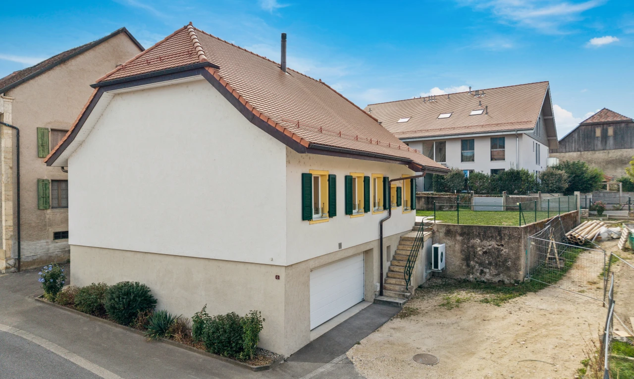 außenansicht mit stuckverkleidung, zaun, eingebaute garage, property visible, und day time