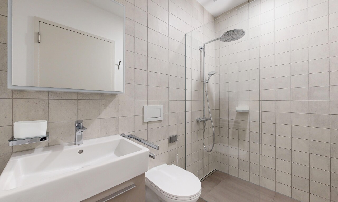 salle de bains avec miroir, douche, salle de bain complète, tile wall, et inside property