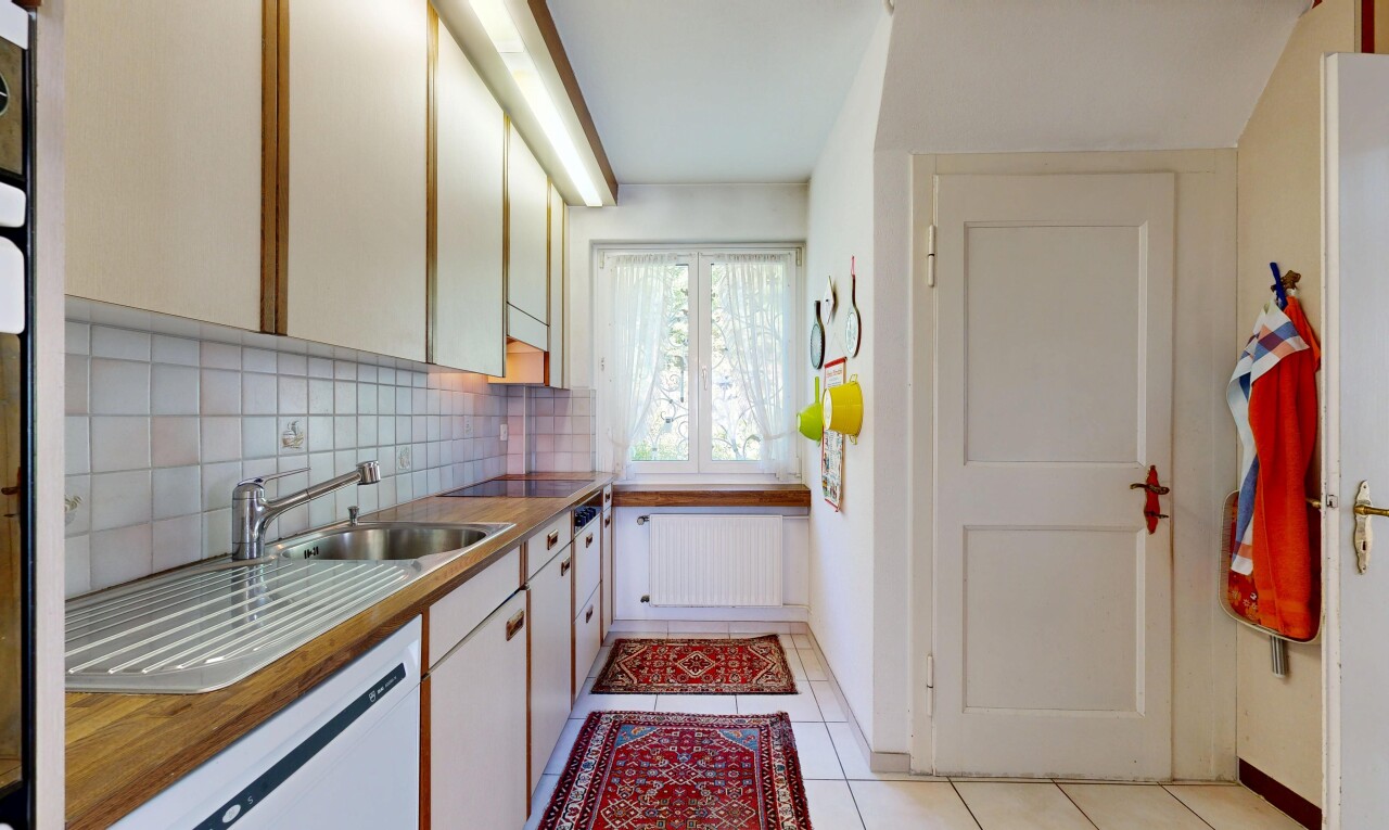 two tone kitchen featuring backsplash, light tile patterned floors, radiator heating unit, dishwasher, and black electric stovetop