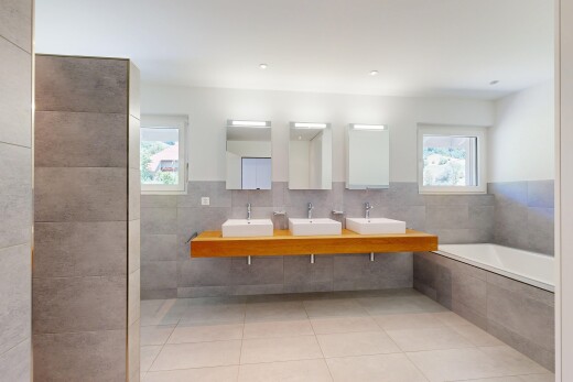 full bathroom featuring double vanity, a bath, light tile patterned flooring, plenty of natural light, and tile walls