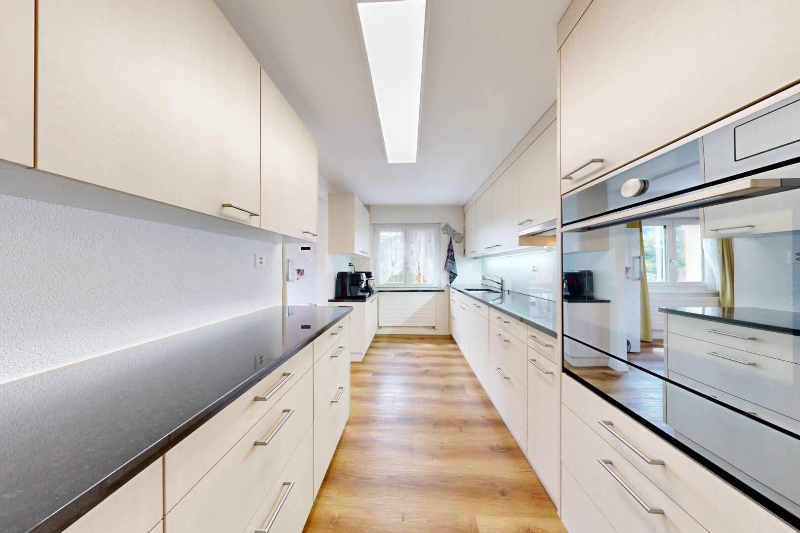 cuisine avec wood finish floor, sol en finition bois, light floor, four, et dark countertops