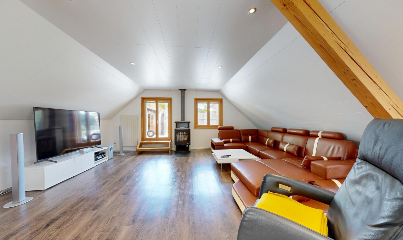 salon avec pièce supplémentaire, sol en finition bois, wood finish floor, télévision, et poêle à bois