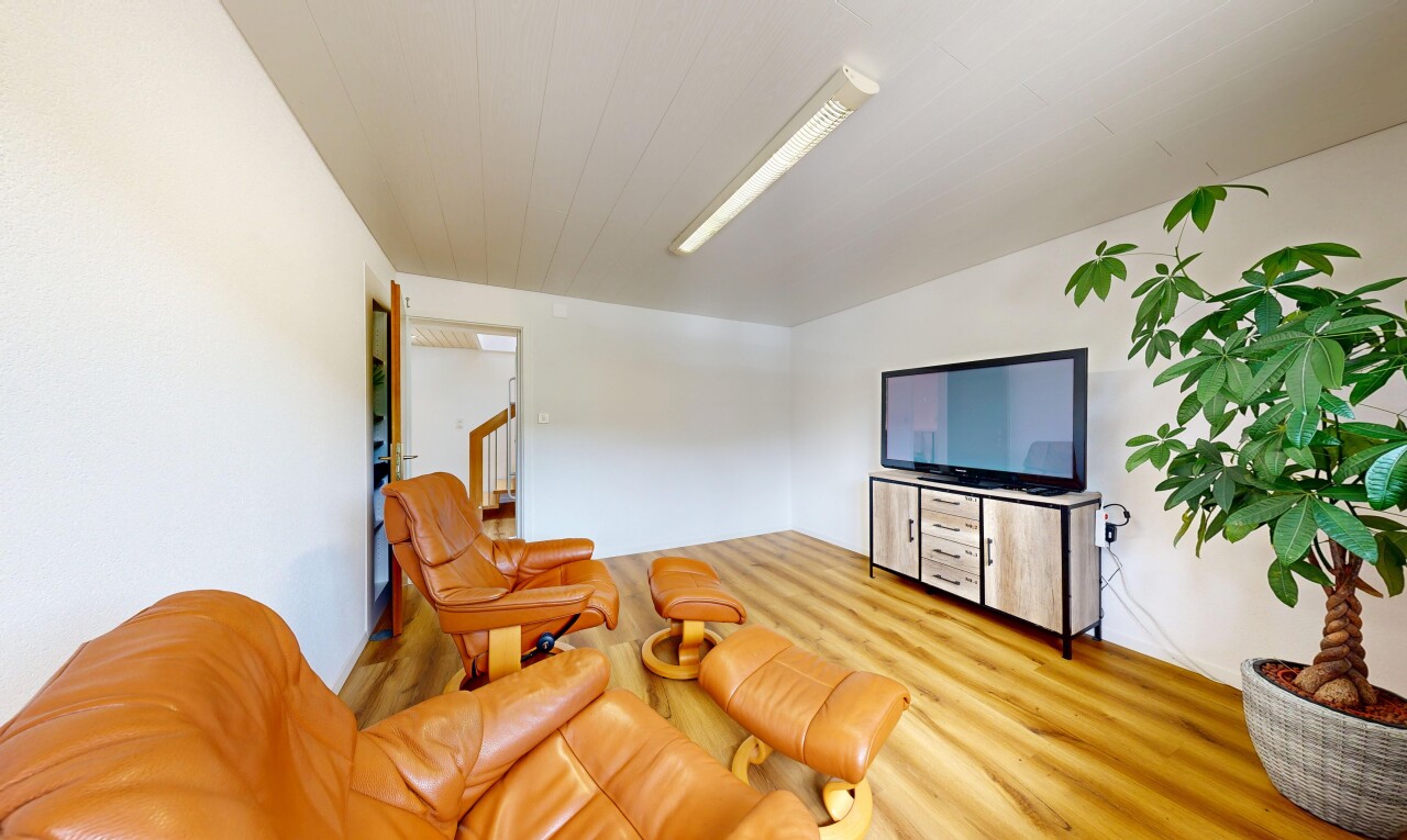 salon avec télévision, sol en finition bois, wood finish floor, escaliers, et cloison sèche