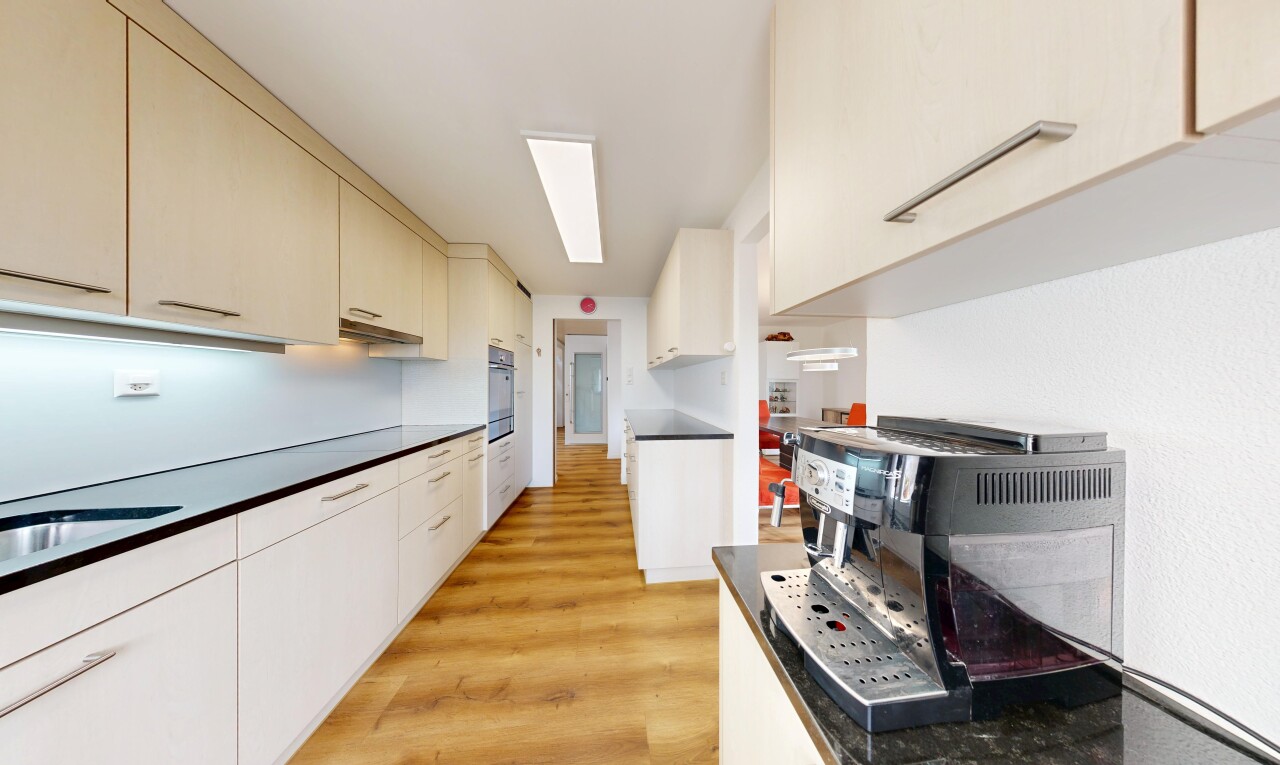 cuisine avec wood finish floor, sol en finition bois, light floor, dark countertops, et plans de travail