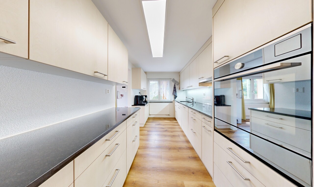 cuisine avec wood finish floor, sol en finition bois, light floor, four, et dark countertops