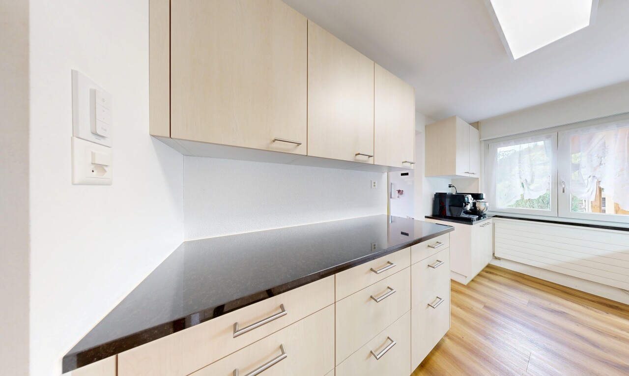cuisine avec dark countertops, plans de travail, light floor, wood finish floor, et sol en finition bois