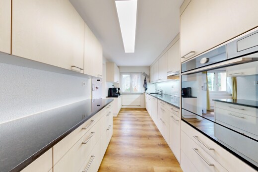 cuisine avec wood finish floor, sol en finition bois, light floor, four, et dark countertops