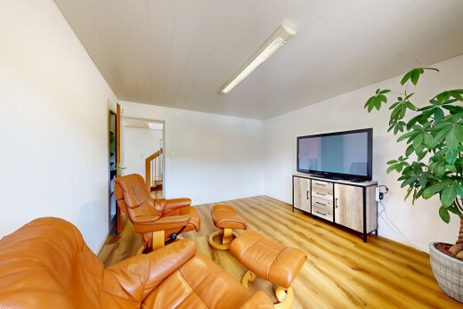 salon avec télévision, sol en finition bois, wood finish floor, escaliers, et cloison sèche
