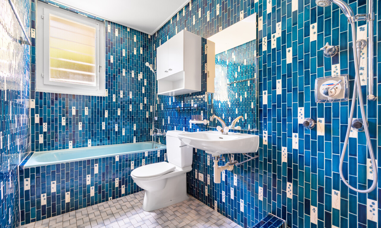 salle de bains avec toilette, tile wall, mur en carrelage, tile tub, et bain