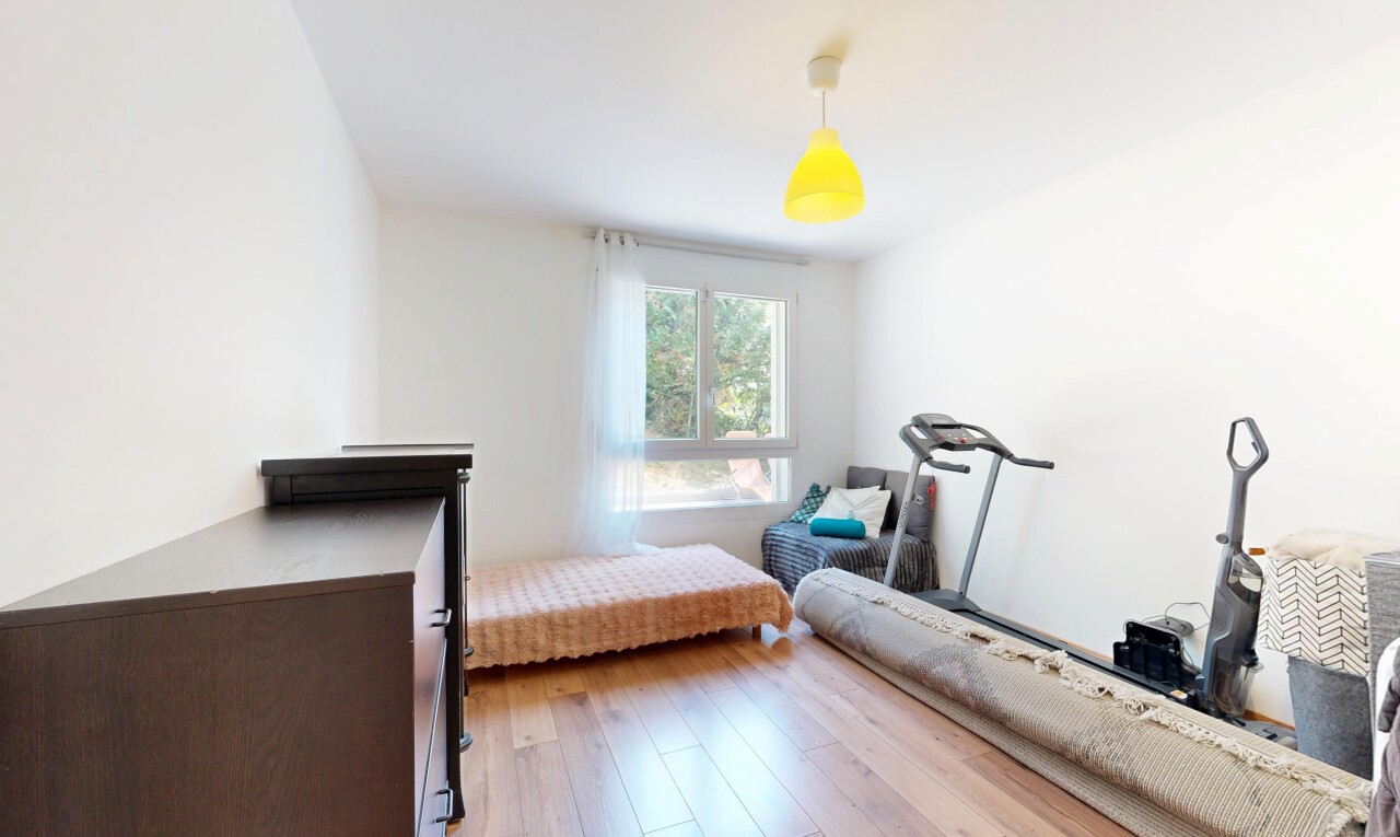 chambre avec éclairage suspendu, drywall, cloison sèche, wood finish floor, et sol en finition bois