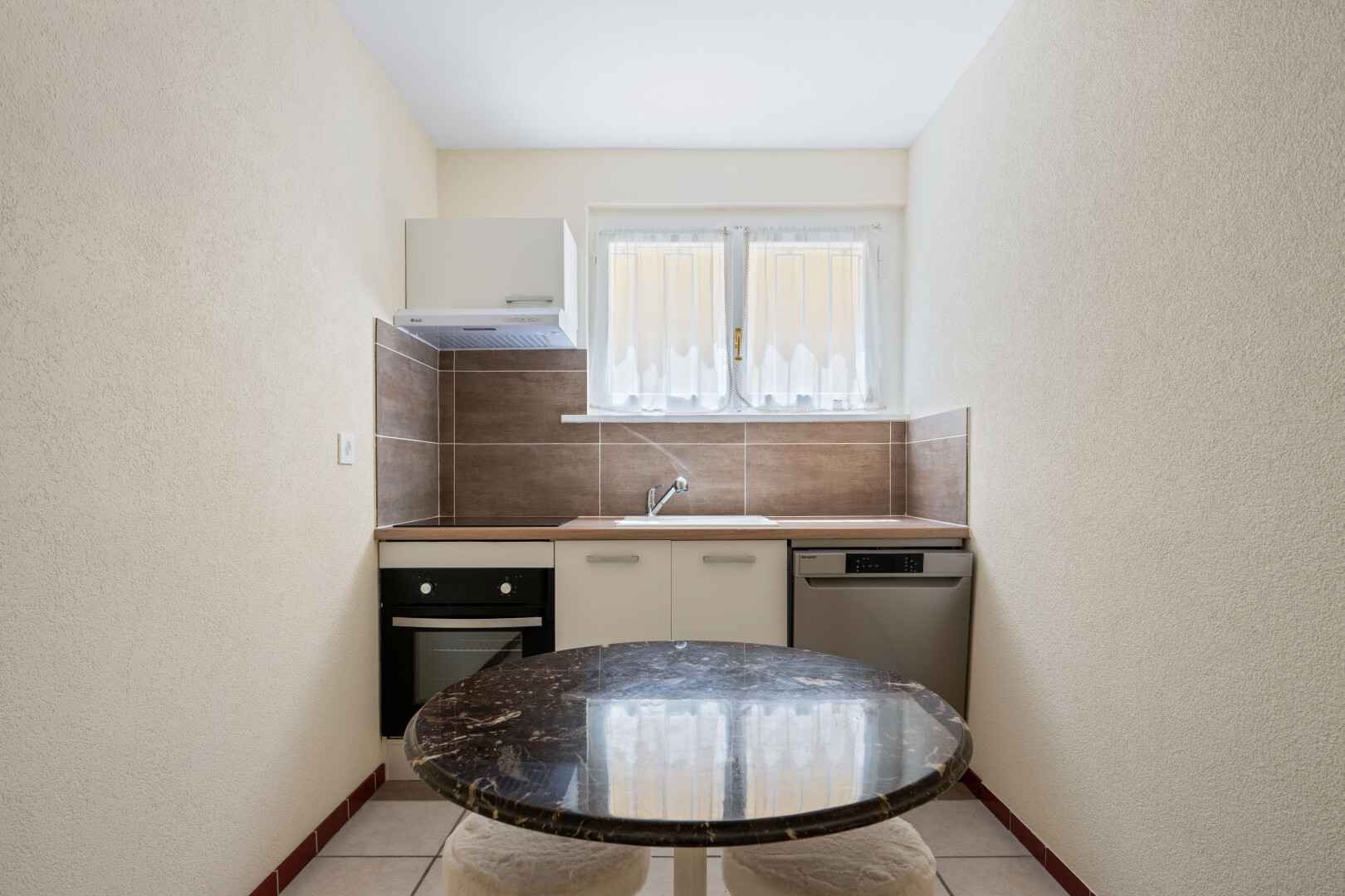cuisine avec mur texturé, textured wall, four, inside property, et light floor