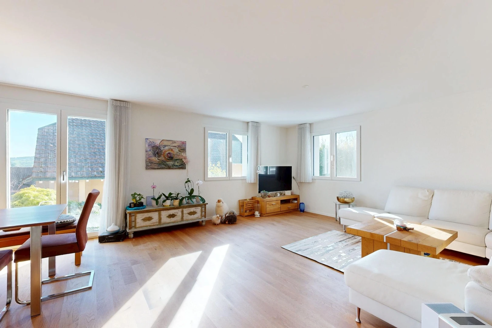 wohn- / esszimmer mit natürliches licht, drywall, gipskartonwand, fernseher, und wood finish floor
