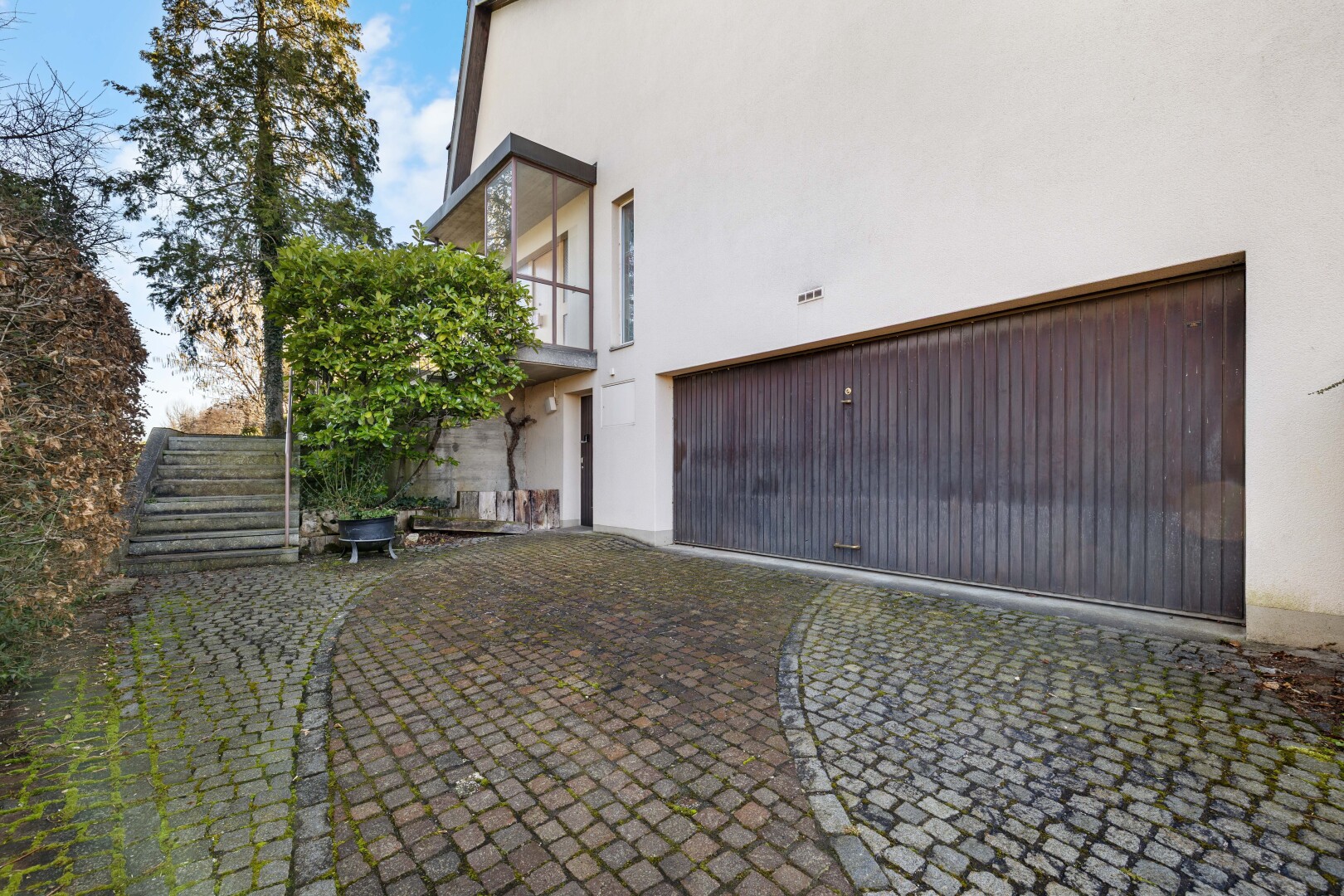 façade avec bardage en stuc, balcon, property visible, garage intégré, et day time