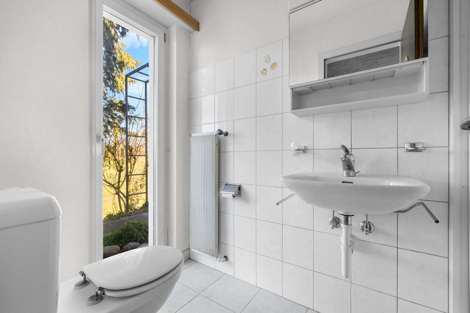 salle de bains avec toilette, miroir, radiateur, mur en carrelage, et tile wall