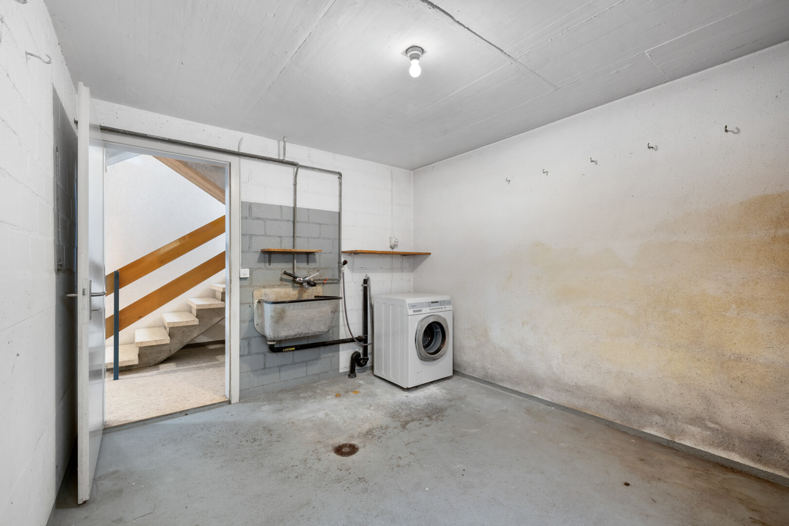 buanderie avec sol en béton, concrete floor, lave-linge et sèche-linge, unfinished concrete floor, et inside property
