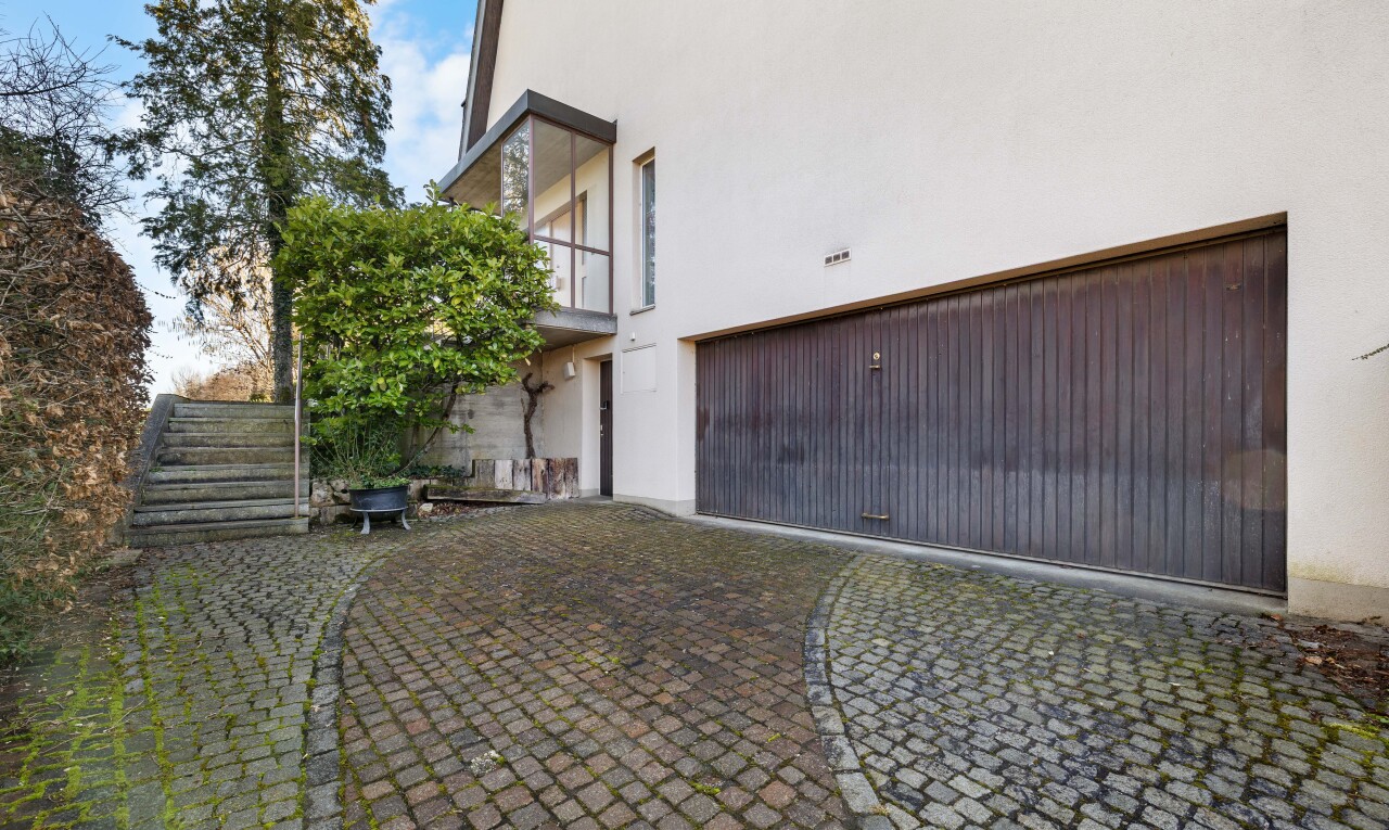 façade avec bardage en stuc, balcon, property visible, garage intégré, et day time