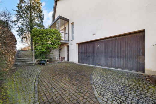 façade avec bardage en stuc, balcon, property visible, garage intégré, et day time
