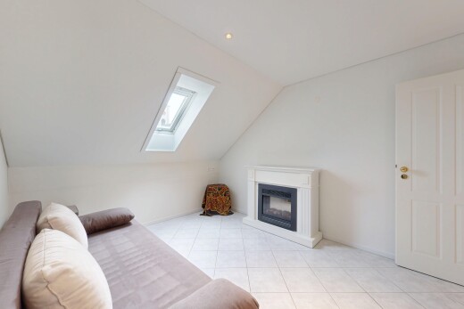 living room with vaulted ceiling, a glass covered fireplace, a skylight, and light tile patterned floors