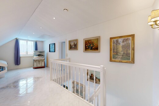 hallway featuring an upstairs landing, light tile patterned flooring, and vaulted ceiling