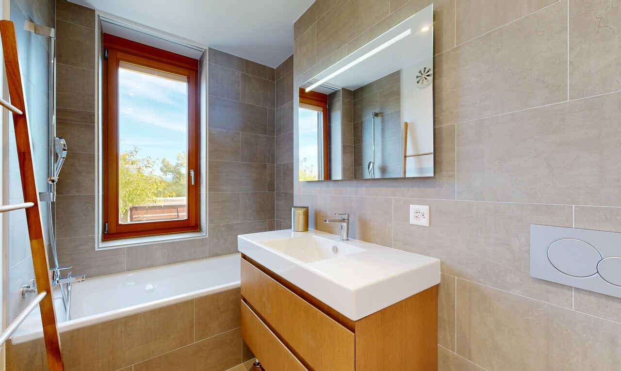 full bathroom featuring vanity, a relaxing tiled tub, tile walls, and a shower