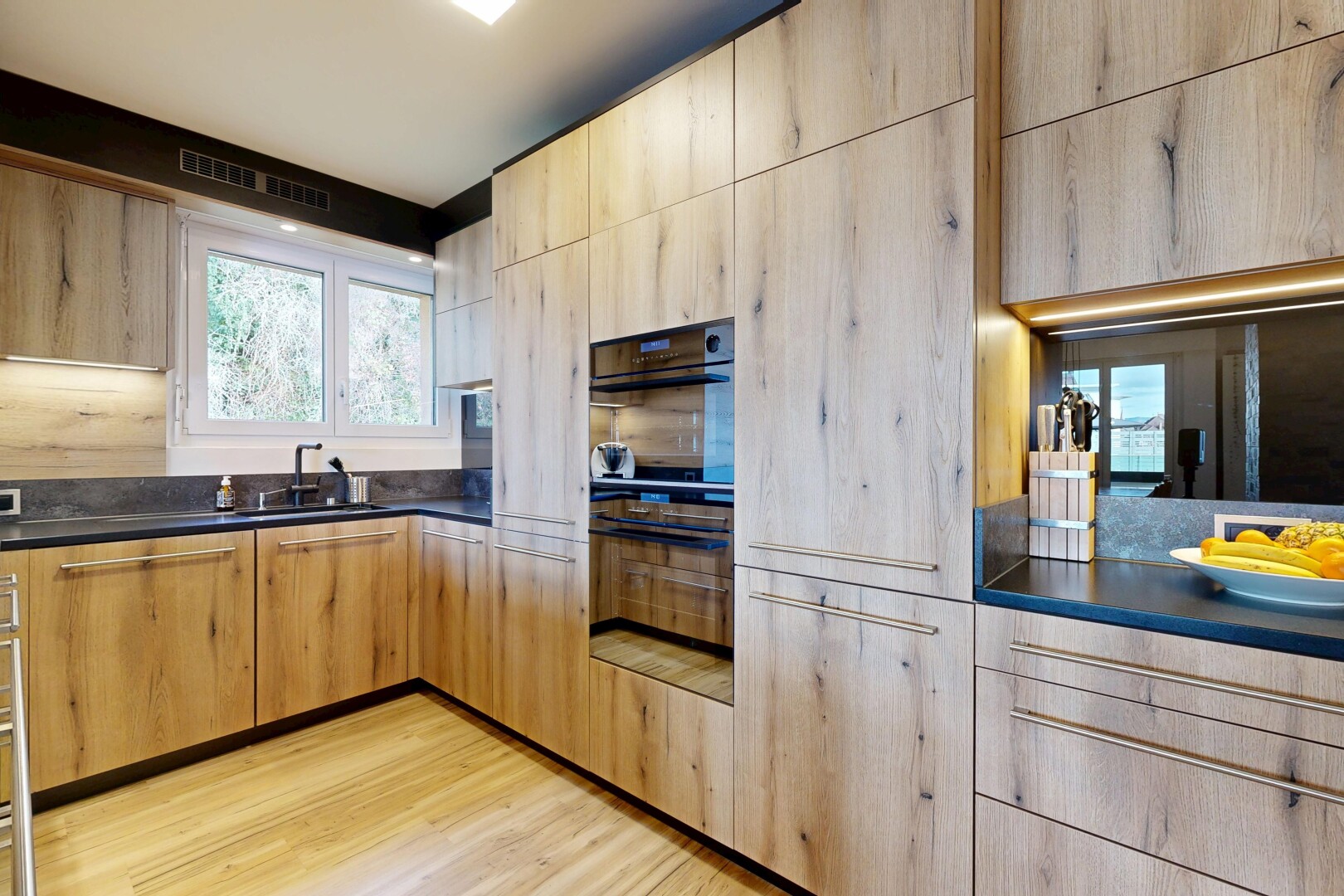 kitchen with dark countertops, light brown cabinetry, light wood finished floors, and modern cabinets