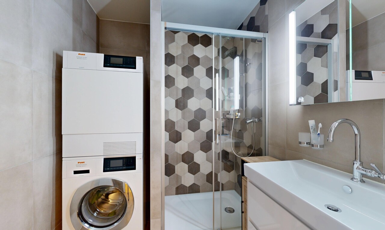 full bath with tile walls, a stall shower, vanity, and estacked washer and dryer