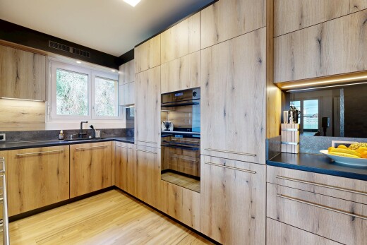 cuisine avec plans de travail, armoires marron clair, four double, sol en finition bois, et wood finish floor