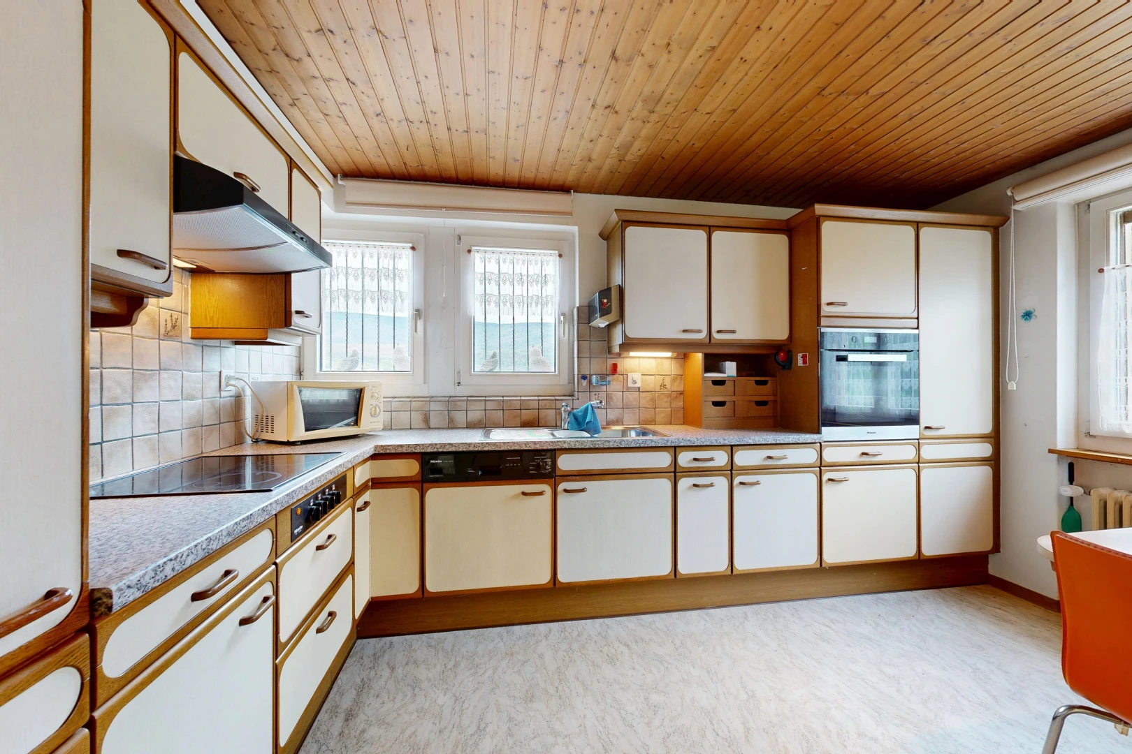 kitchen featuring light countertops, two tone cabinets, oven, wooden ceiling, and white microwave