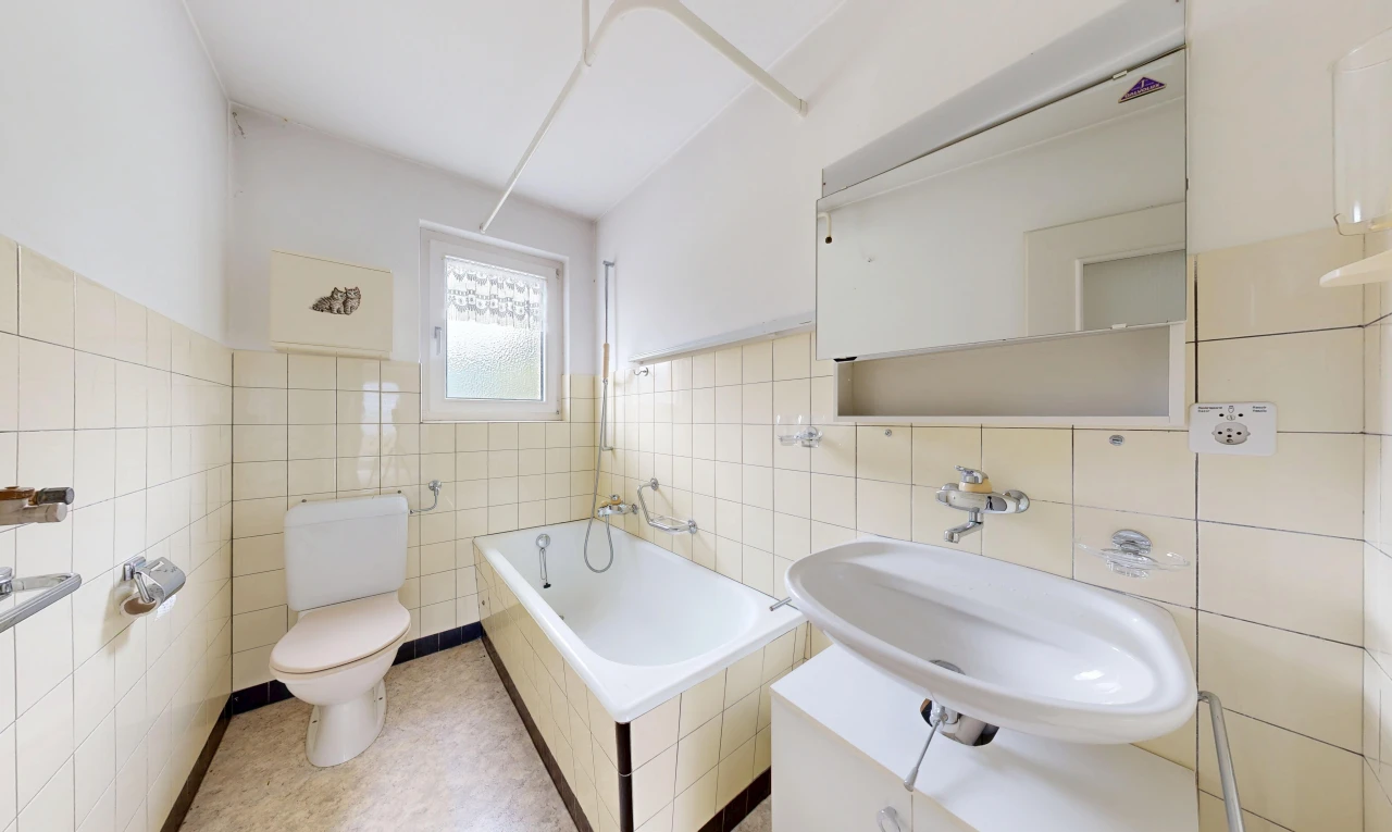 bathroom featuring a relaxing tiled tub, tile walls, and wainscoting