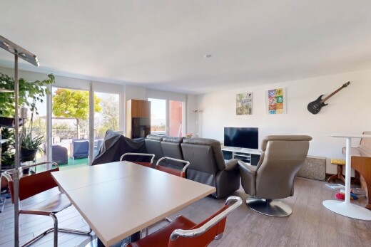 salon / salle à manger avec télévision, accès à l'extérieur, cloison sèche, drywall, et sol en finition bois