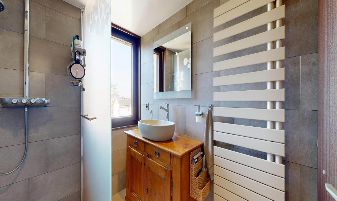 salle de bains avec lavabo (ou coiffeuse selon le contexte), miroir, radiateur, chauffe-serviettes, et évier