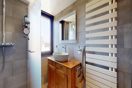 salle de bains avec lavabo (ou coiffeuse selon le contexte), miroir, radiateur, chauffe-serviettes, et évier