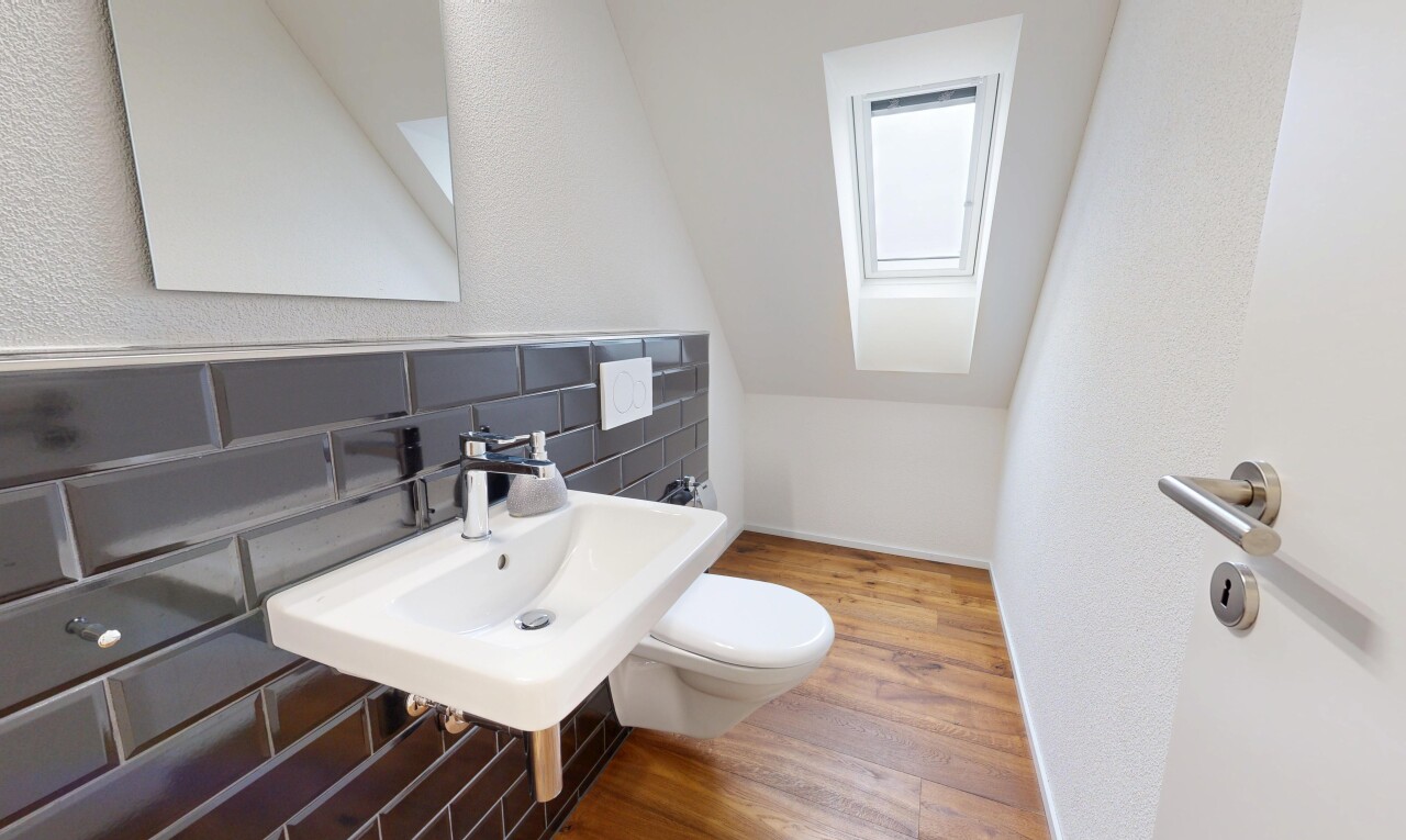 salle de bains avec puits de lumière, miroir, wood finish floor, sol en finition bois, et toilette