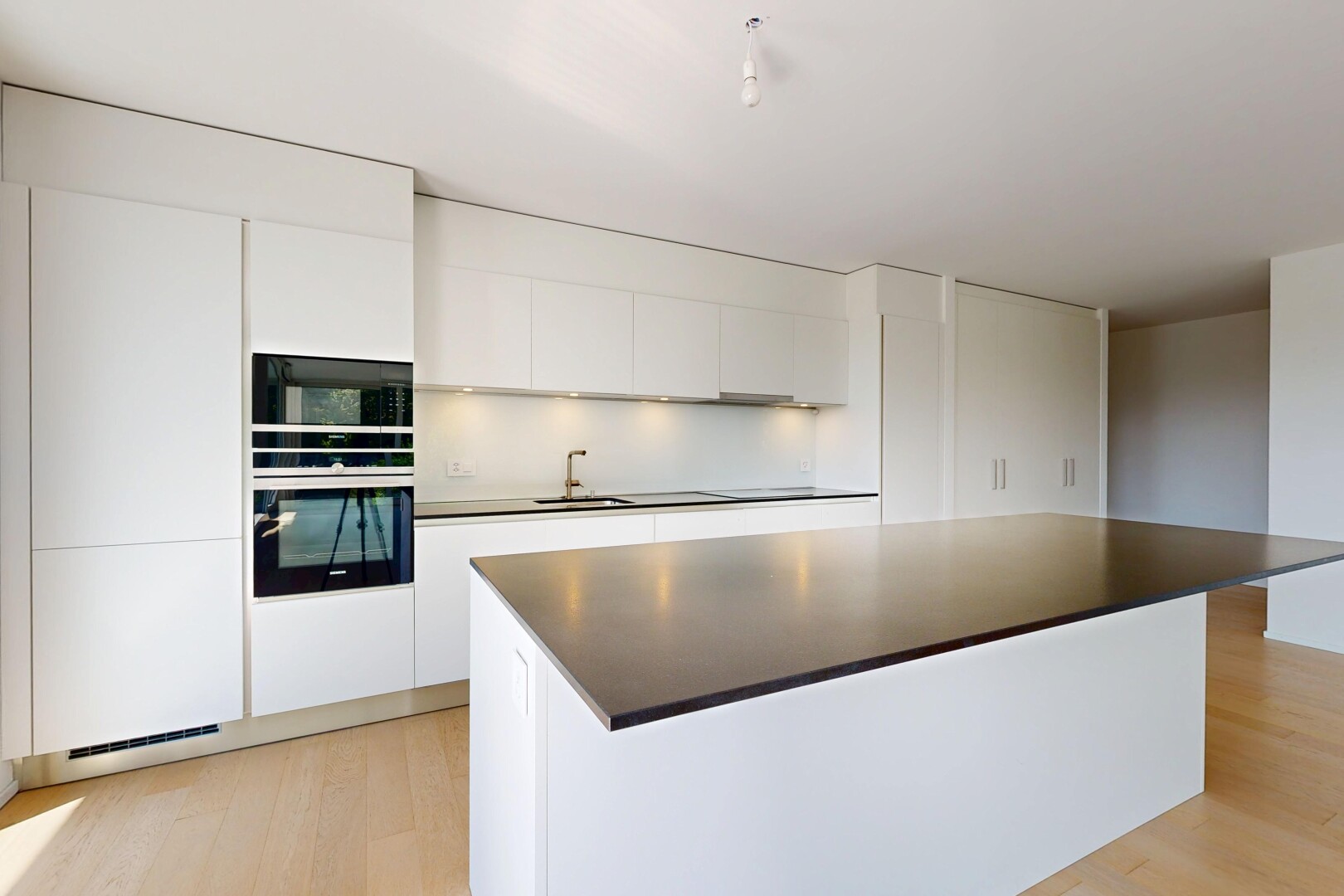 cuisine avec light floor, armoires à panneau plat, flat panel cabinets, four, et sol en finition bois