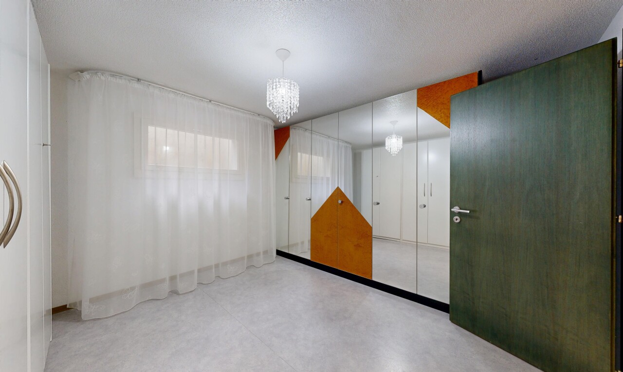 chambre avec lustre remarquable, inside property, sol en béton, concrete floor, et cloison sèche