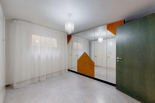 chambre avec lustre remarquable, inside property, sol en béton, concrete floor, et cloison sèche