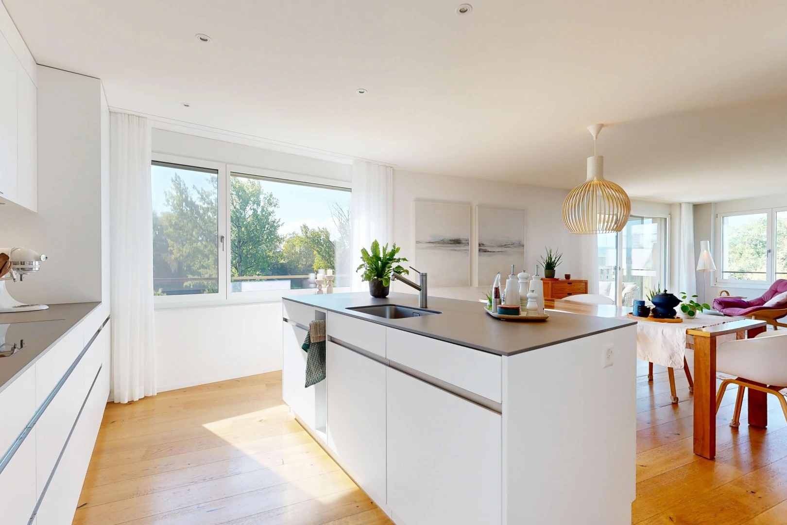 kitchen featuring white cabinets, an island with sink, dark countertops, and light wood-style floors