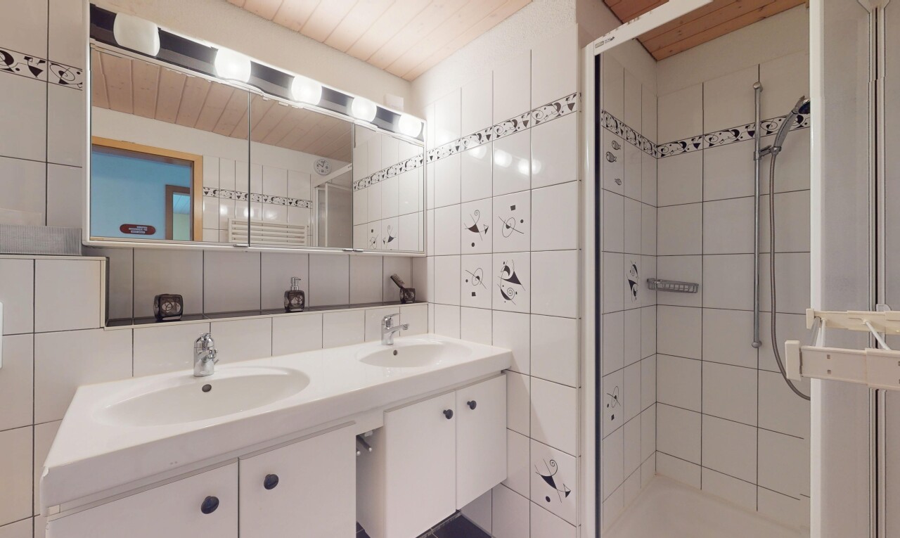 salle de bains avec évier, tile wall, mur en carrelage, douche, et inside property