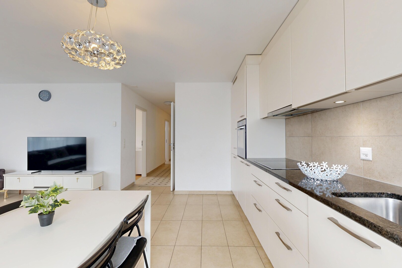 cuisine avec lustre remarquable, armoires blanches, télévision, tile floor, et sol en carrelage