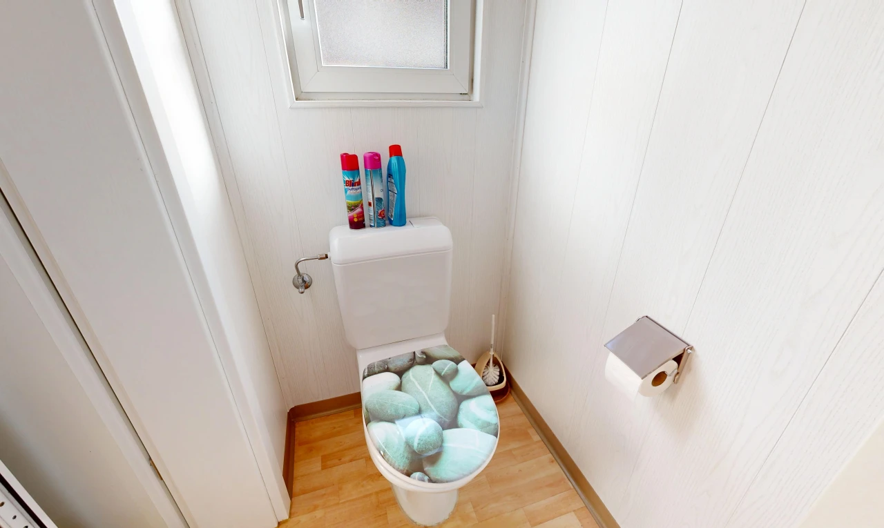 salle de bains avec toilette, sol en finition bois, wood finish floor, inside property, et light floor