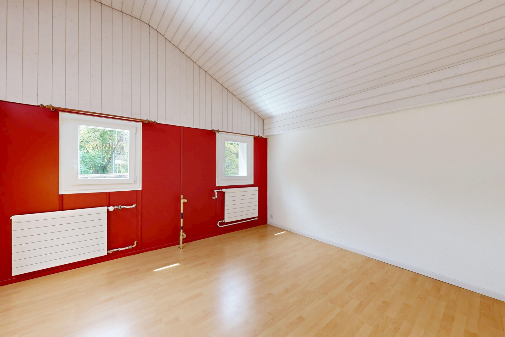 pièce vide avec vaulted ceiling, plafond voûté, radiateur, lumière naturelle, et wood finish floor