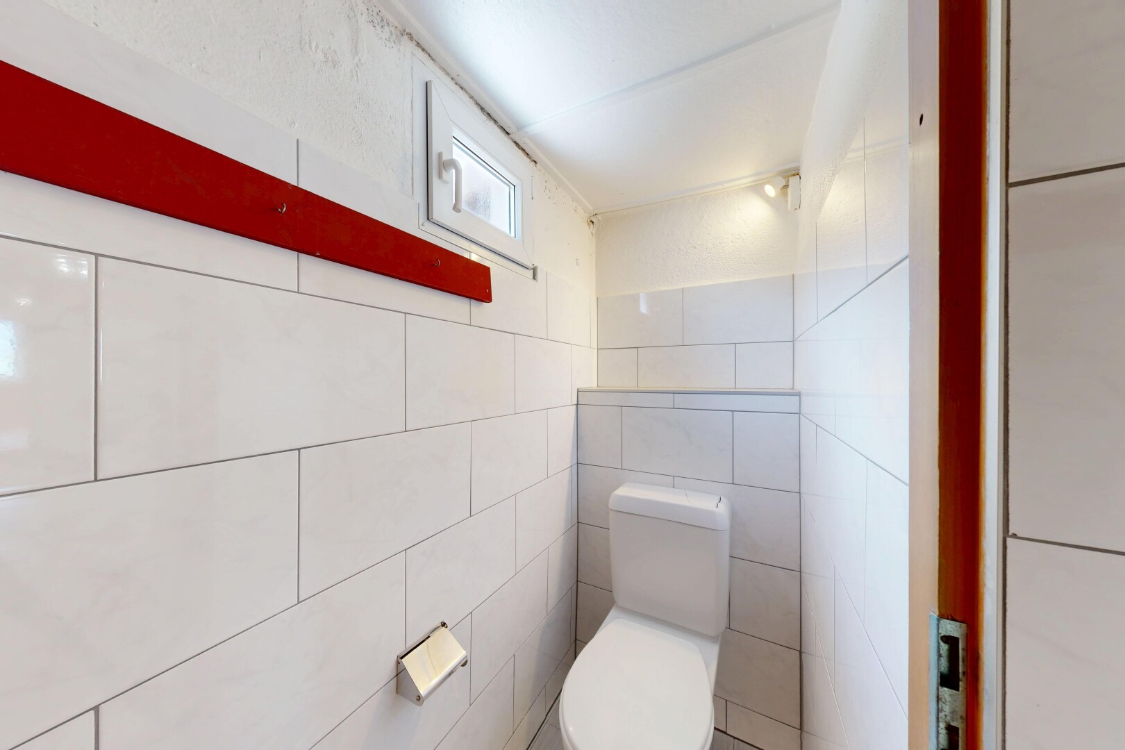 salle de bains avec toilette, inside property, mur en carrelage, tile wall, et lumière naturelle