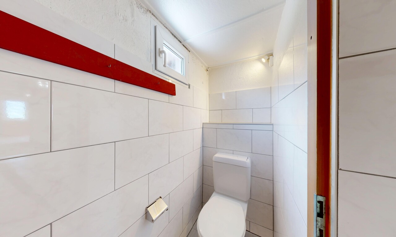 salle de bains avec toilette, inside property, mur en carrelage, tile wall, et lumière naturelle