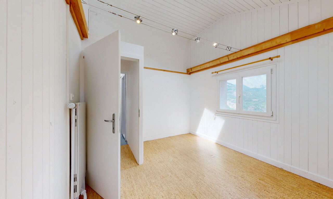 pièce vide avec éclairage sur rail, mur en bois, wood wall, plafond voûté, et vaulted ceiling