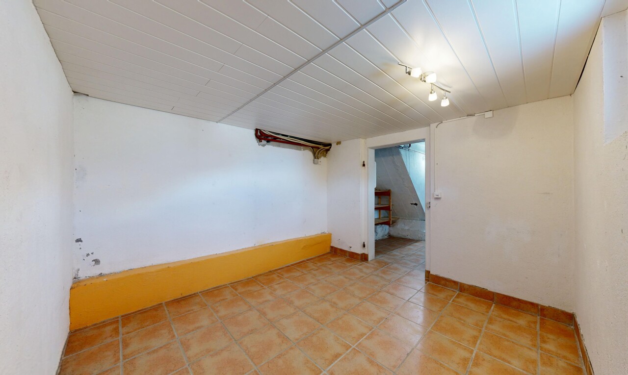 pièce vide avec éclairage sur rail, drywall, cloison sèche, sous-sol, et escaliers
