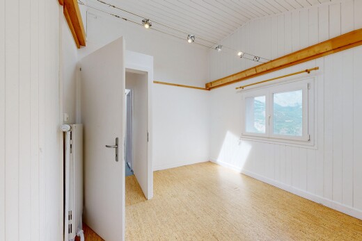pièce vide avec éclairage sur rail, mur en bois, wood wall, plafond voûté, et vaulted ceiling